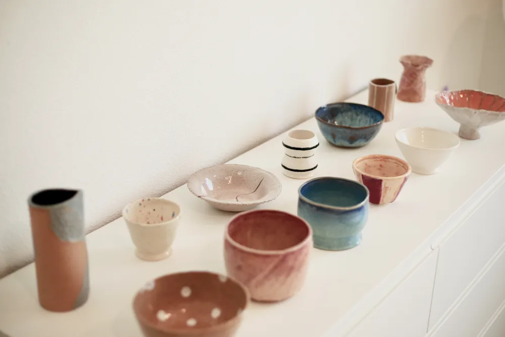 Handmade ceramics at home — bowls, plates and cups on a shelf