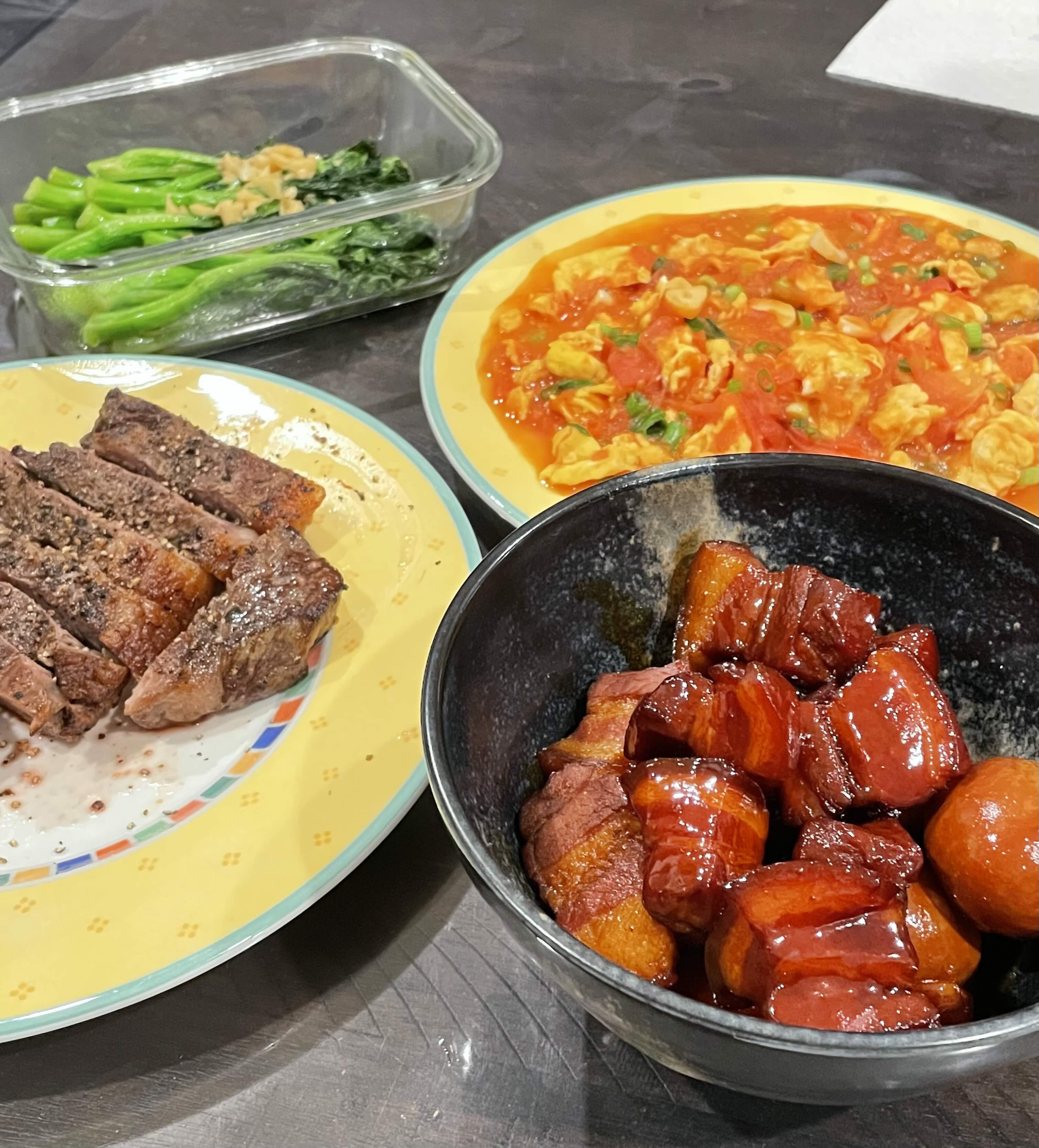 A home-cooked dinner — steak, tomato egg, greens and braised pork